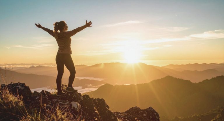 Personne bras ouverts au sommet d une montagne face au lever du soleil symbole de reussite